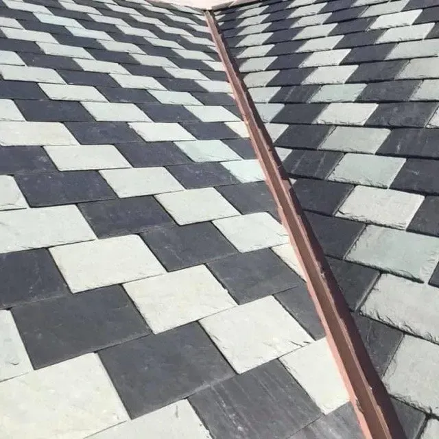 Checkerboard-patterned slate roof in shades of gray and white, with a copper valley flashing.