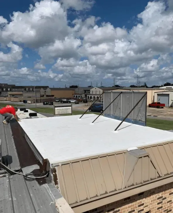 White flat roof with metal sides, against a blue sky with clouds.