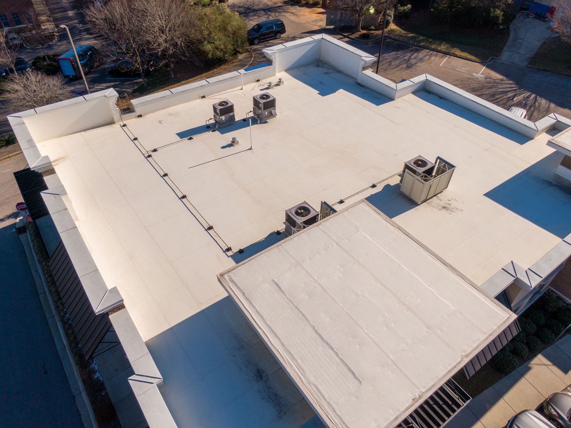Aerial view of a flat white commercial roof with HVAC units.