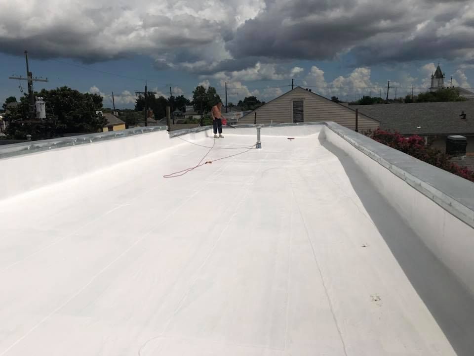 White flat roof with a person, sky, buildings.