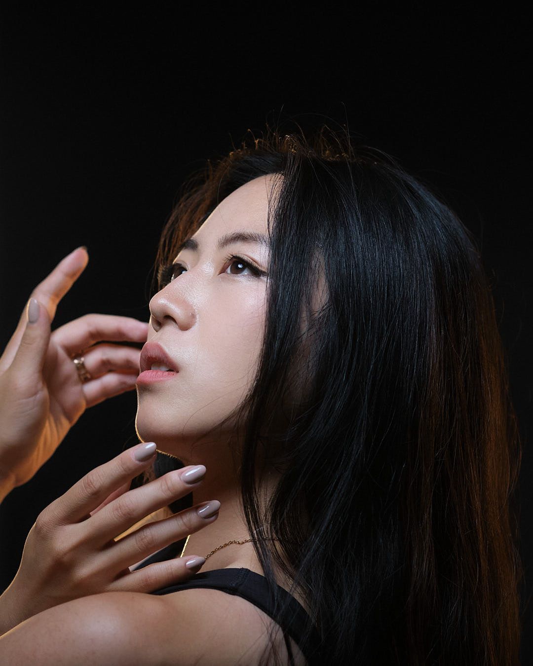 NYC model Minnie Lee — resting head on a rock, looking at the camera. Long dark hair, wearing a blue dress, outdoors. Fashion editorial photographed by Alexis Pesante