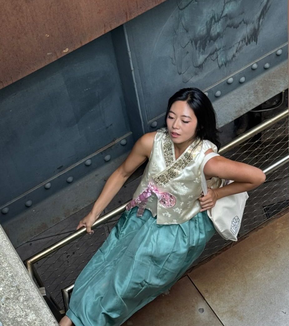Woman in traditional Korean dress hanbok walking down metal stairs of NYC High Line.