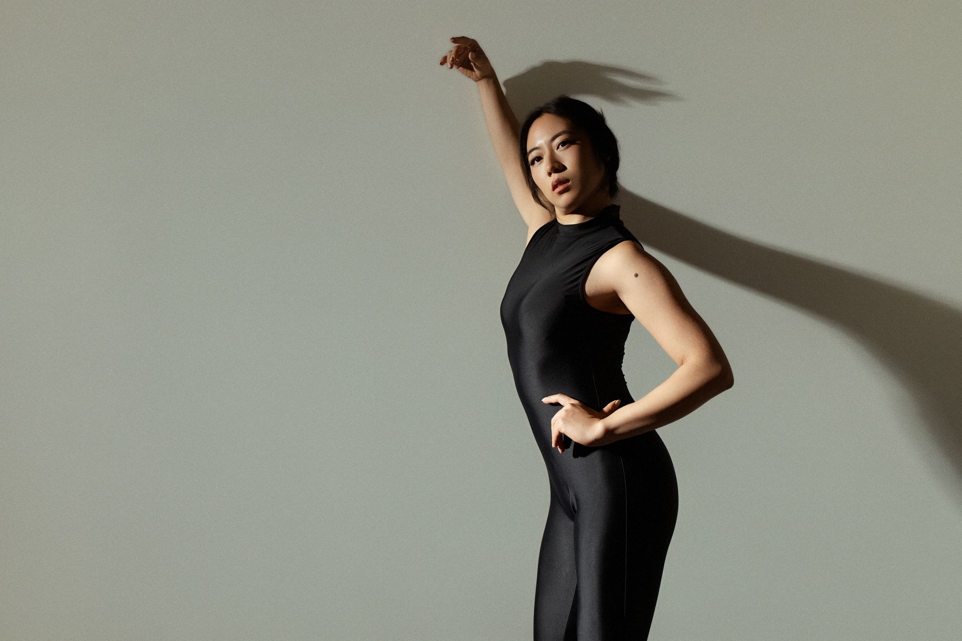 Ballet dancer in pink dress leaps, blurred motion effect against dark background.