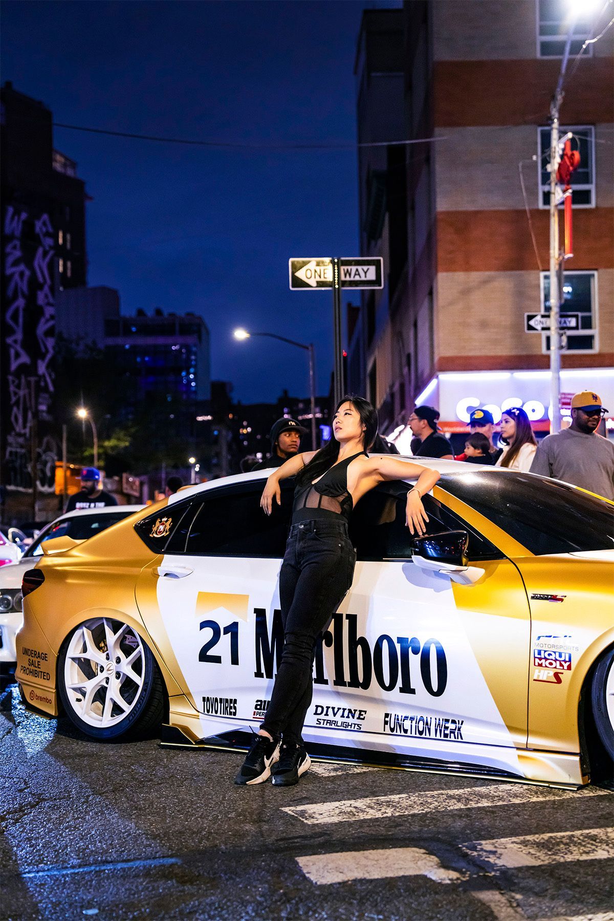 Minnie Lee — NYC car model leaning on  a gold-and-white East Coast Legends Marlboro car at  NYC Daikoku car meet, photography portrait by Josanna Uy.