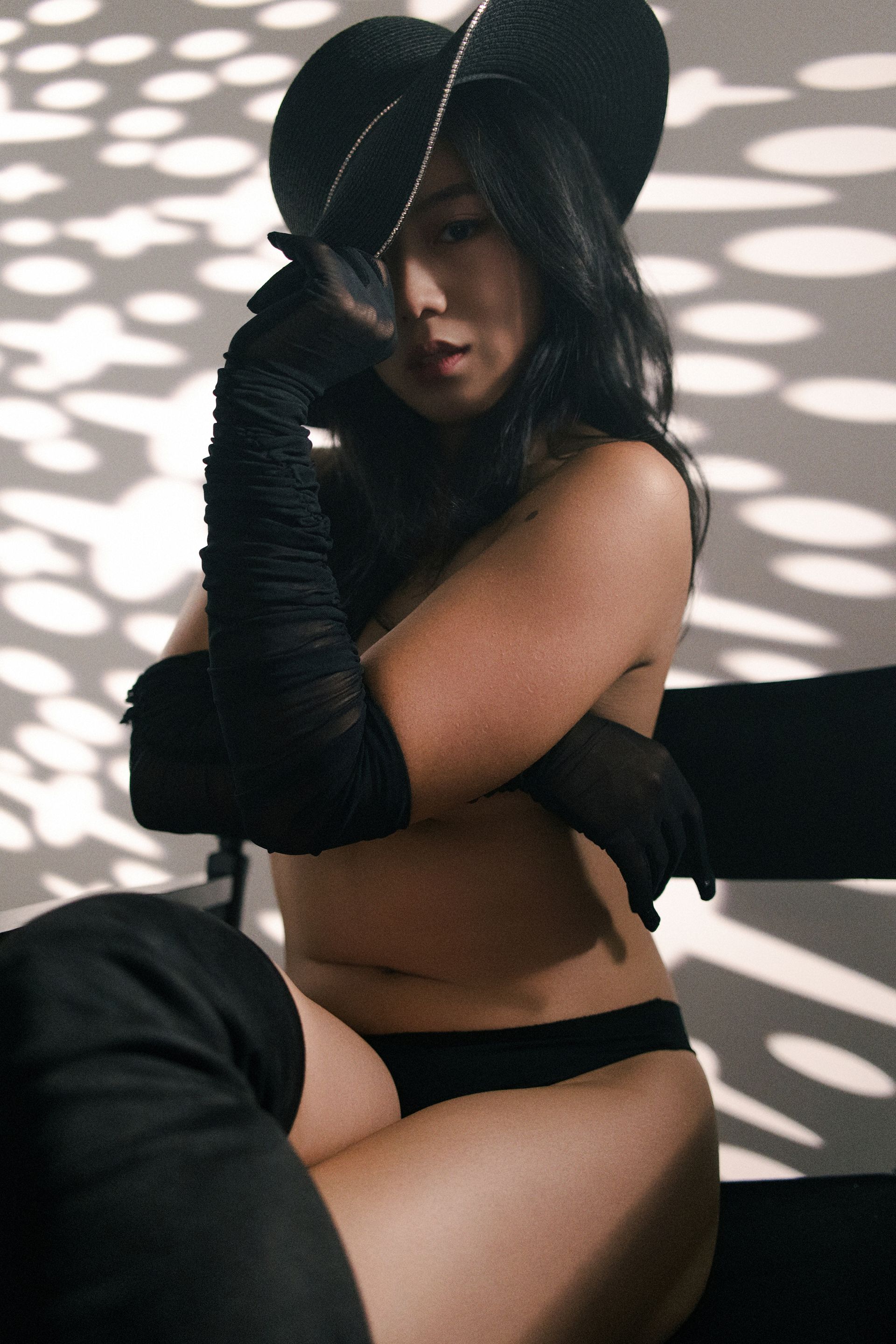 NYC model Minnie Lee in an elegant  fine-art nude inspired by Breakfast at Tiffany’s — styled with a black hat, and long black gloves. Her pose radiates timeless sophistication, cinematic grace, and subtle sensuality, captured by Photographed by Orion Mckinley Phillips II in a luxury editorial style.