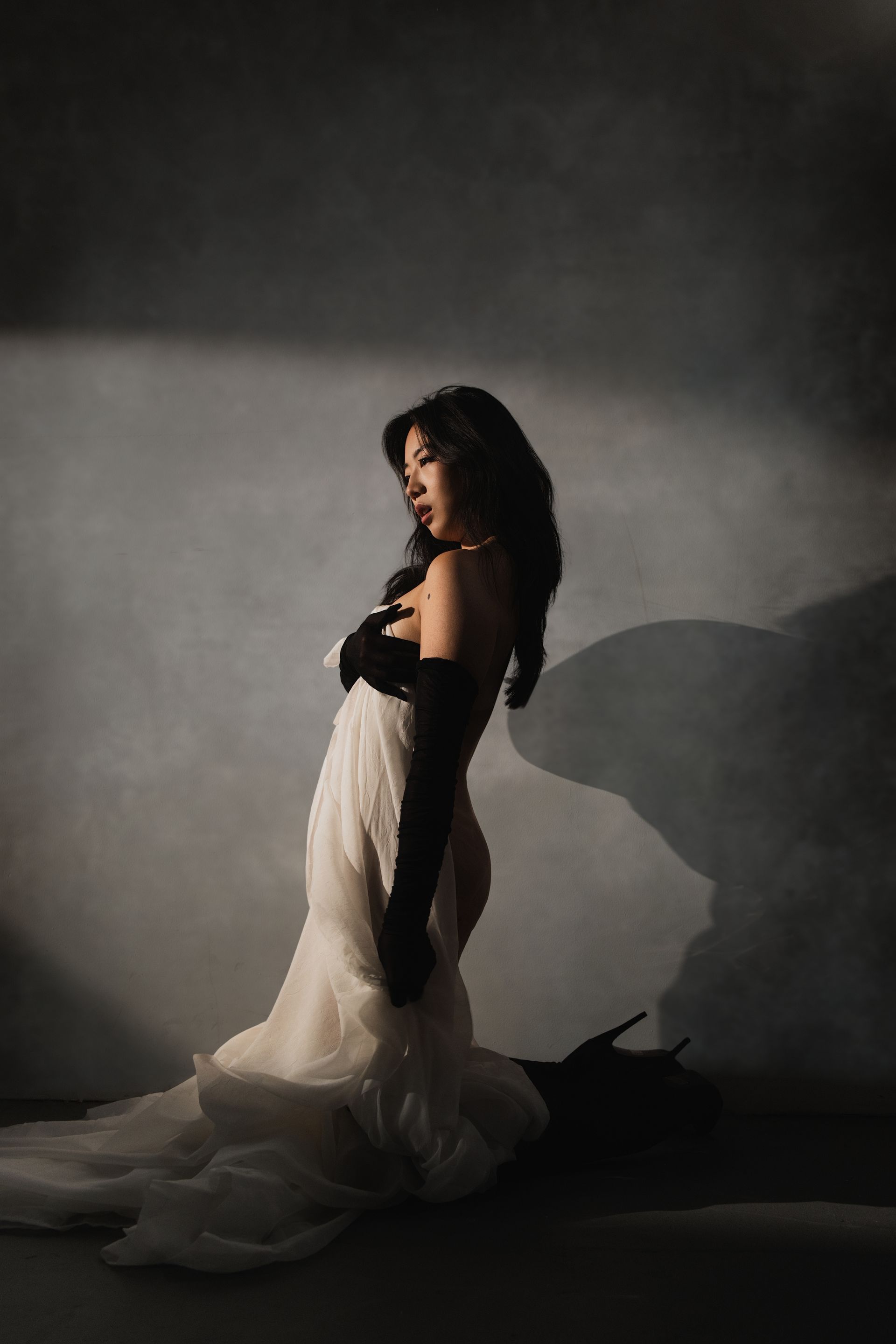 Professional NYC model Minnie Lee posing with expressive movement under dramatic lighting, captured with flowing fabric and sculptural shadows to highlight control, form, and artistic elegance.