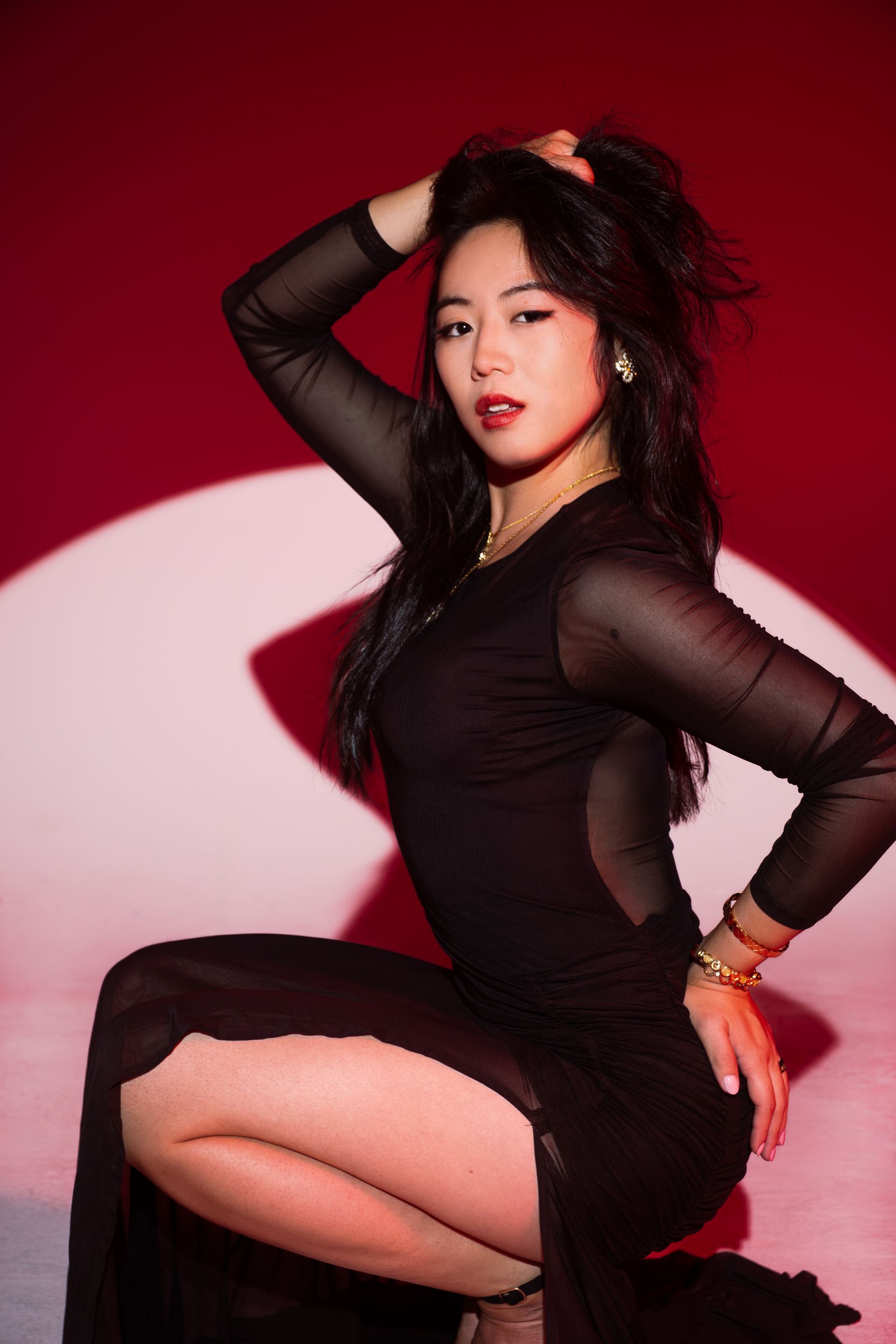 Luxury editorial portrait in controlled red studio light, disciplined posture and sculptural lines, model Minnie Lee.