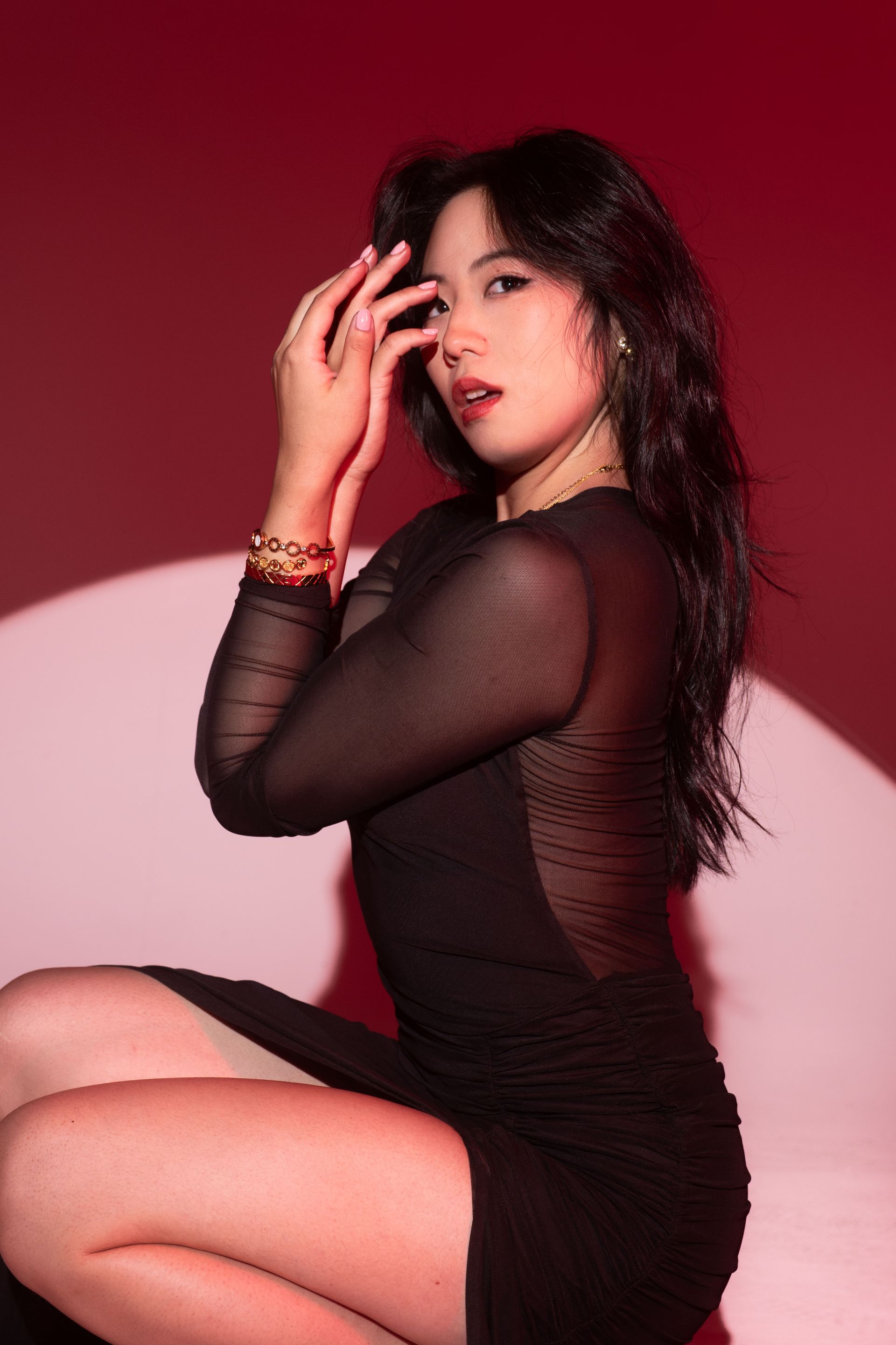 Campaign-ready studio editorial with controlled movement, red backdrop, performance-driven posing — Minnie Lee.