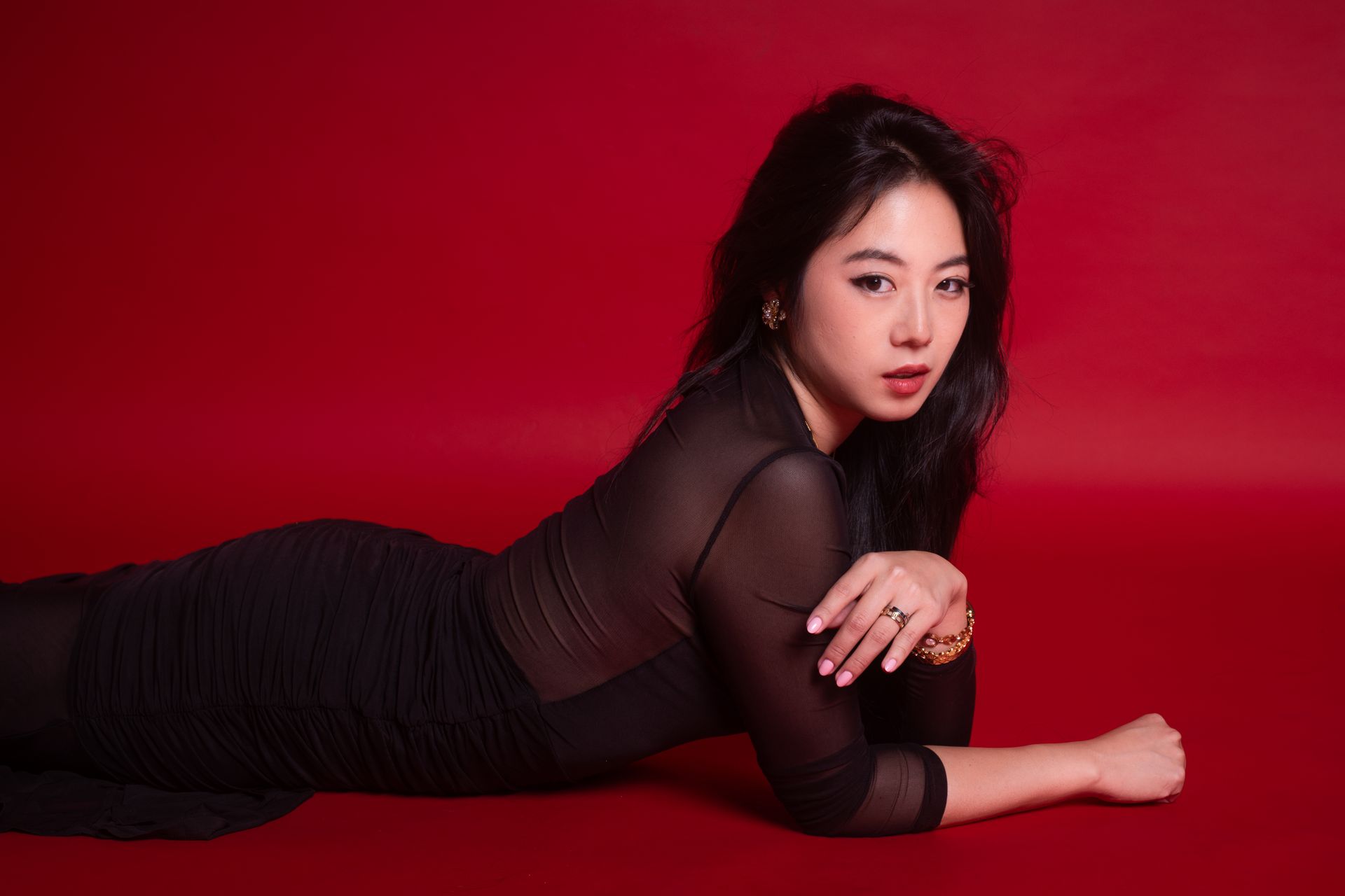 Campaign-ready studio editorial with controlled movement, red backdrop, performance-driven posing — Minnie Lee.