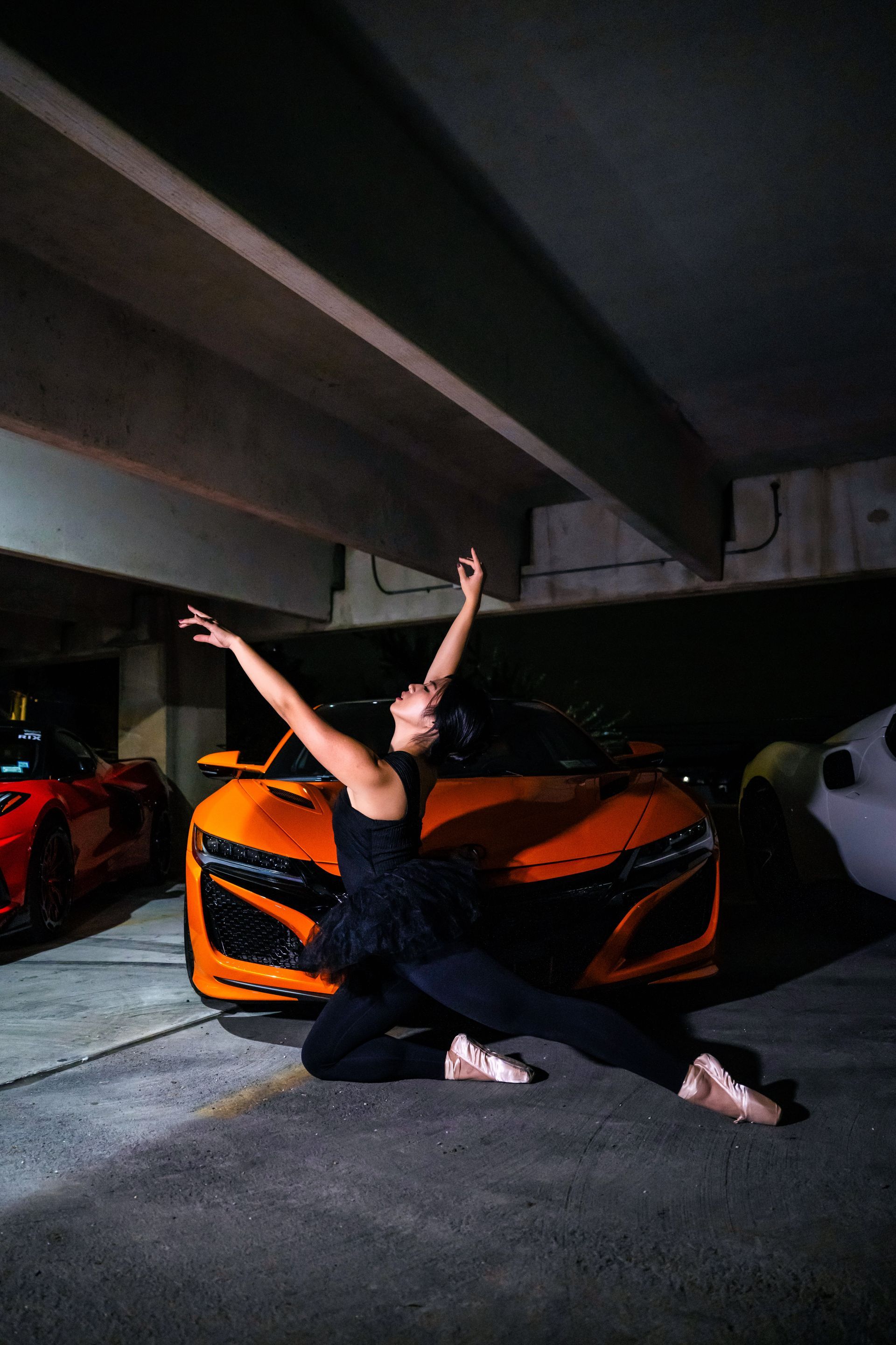 Model Minnie Lee performing ballet en pointe in front of an orange Acura NSX during the Cars x Ballet shoot at the Checkm8 car meet, photographed by Josanna Uy