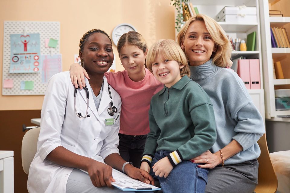 Doctor smiling with three children in a bright clinic office