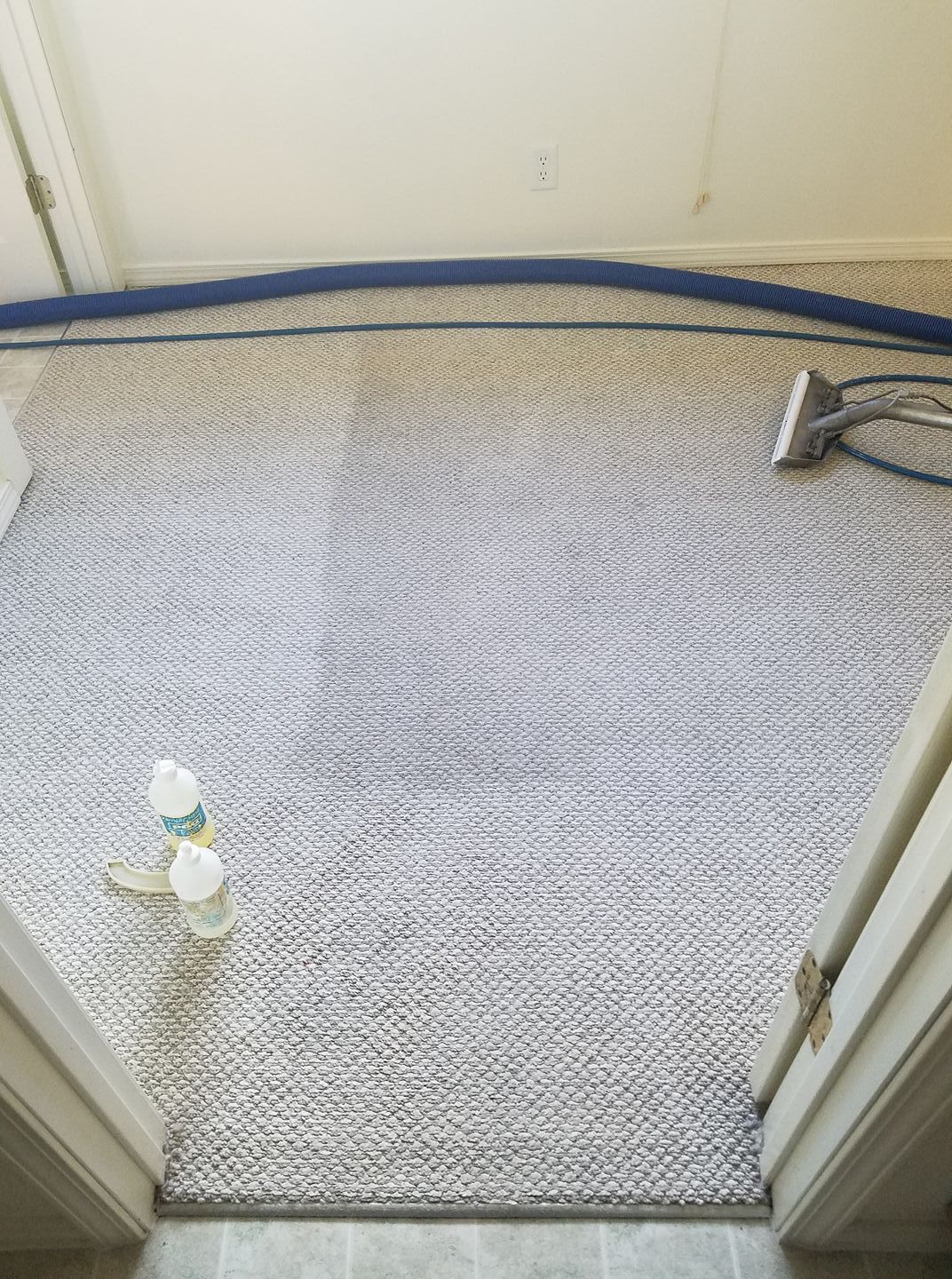 A bottle of water is sitting on the floor next to a vacuum cleaner.