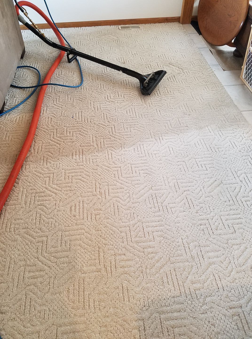 A vacuum cleaner is being used to clean a carpet in a living room.