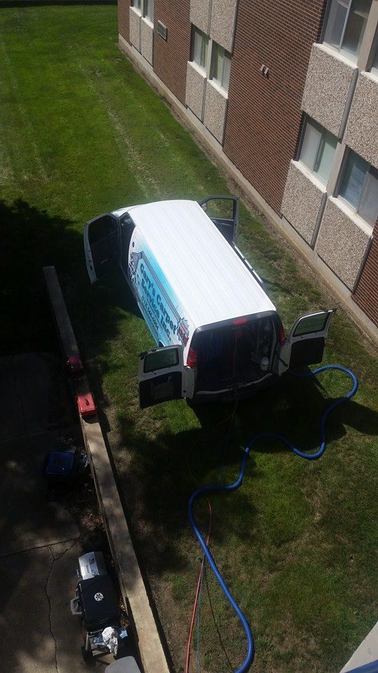 A white van is parked in the grass in front of a building.