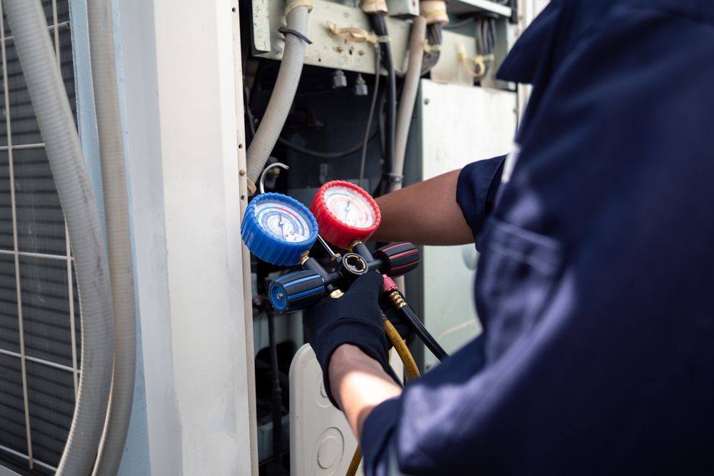 HVAC technician connecting gauges to an air conditioning unit.