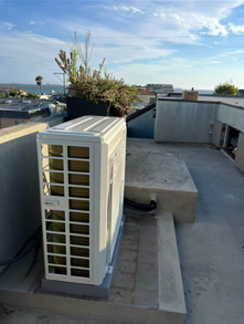 Outdoor air conditioning unit, white, with a fan grill.