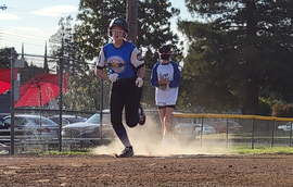 Baseball player sliding into home plate, catcher in front. Blue and gold uniforms, action shot.