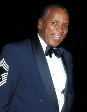 A man in a tuxedo and bow tie smiles for the camera