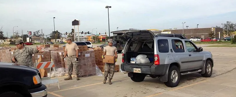 A group of soldiers are loading boxes into a car in a parking lot.