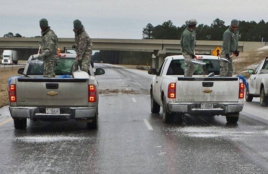 A group of soldiers are standing in the backs of pickup trucks
