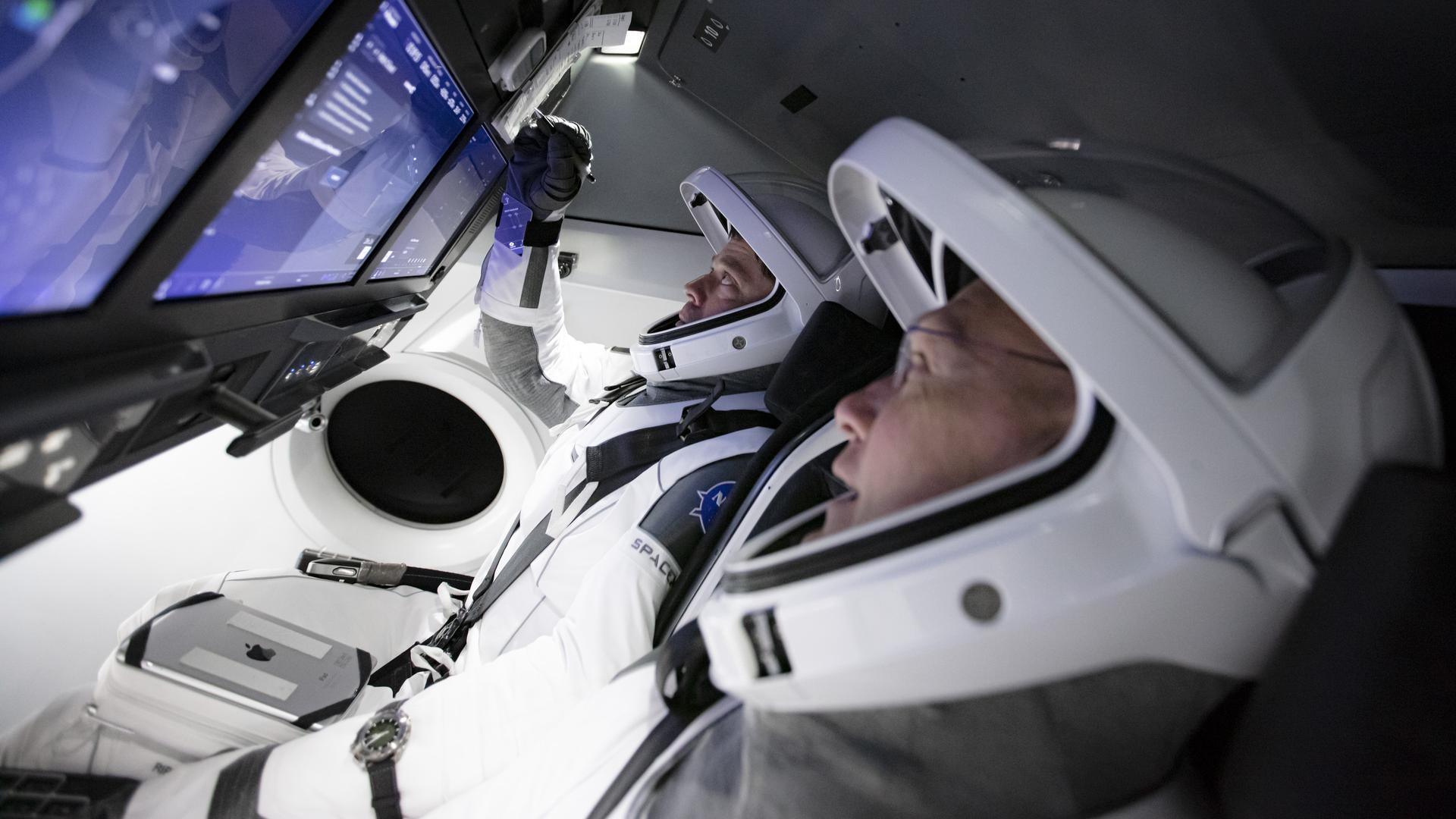 A man in a space suit is sitting in a cockpit.