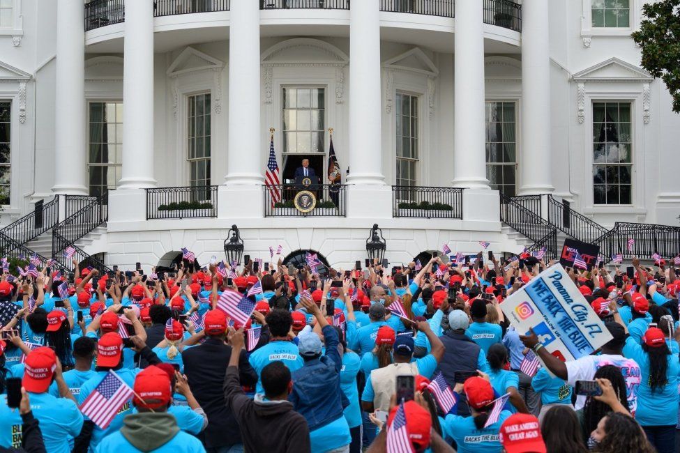 A large group of people are standing in front of the white house.