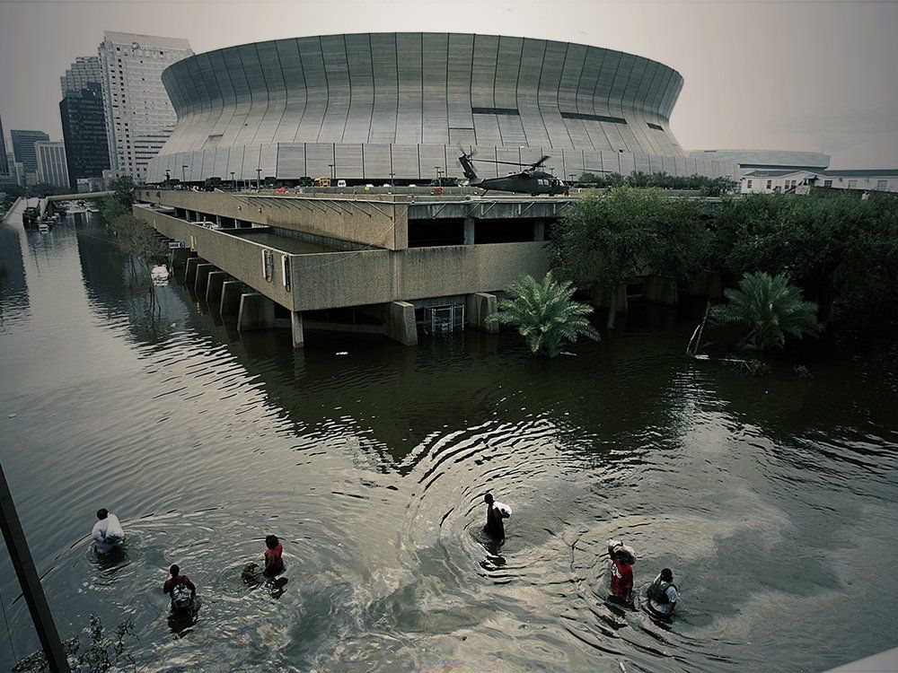 People are swimming in a flooded area in front of a large building
