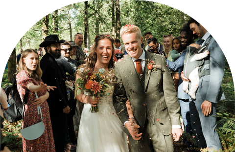 A bride and groom are walking through a crowd of people at their wedding.