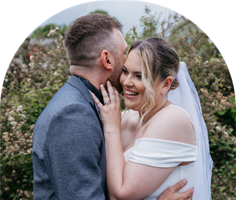 A bride and groom are kissing in a field of flowers.