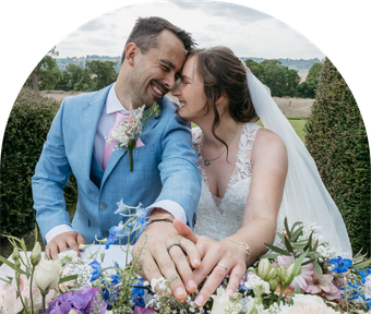 A bride and groom are holding hands in front of a bouquet of flowers.