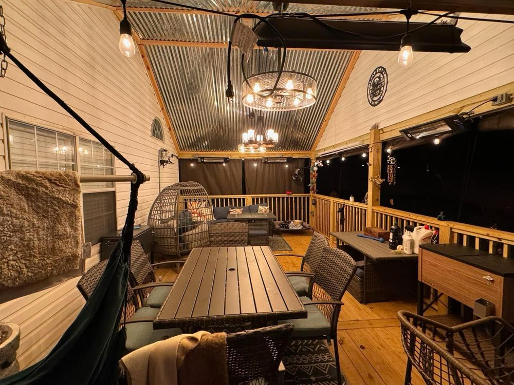 A patio with a table and chairs and a hammock hanging from the ceiling.