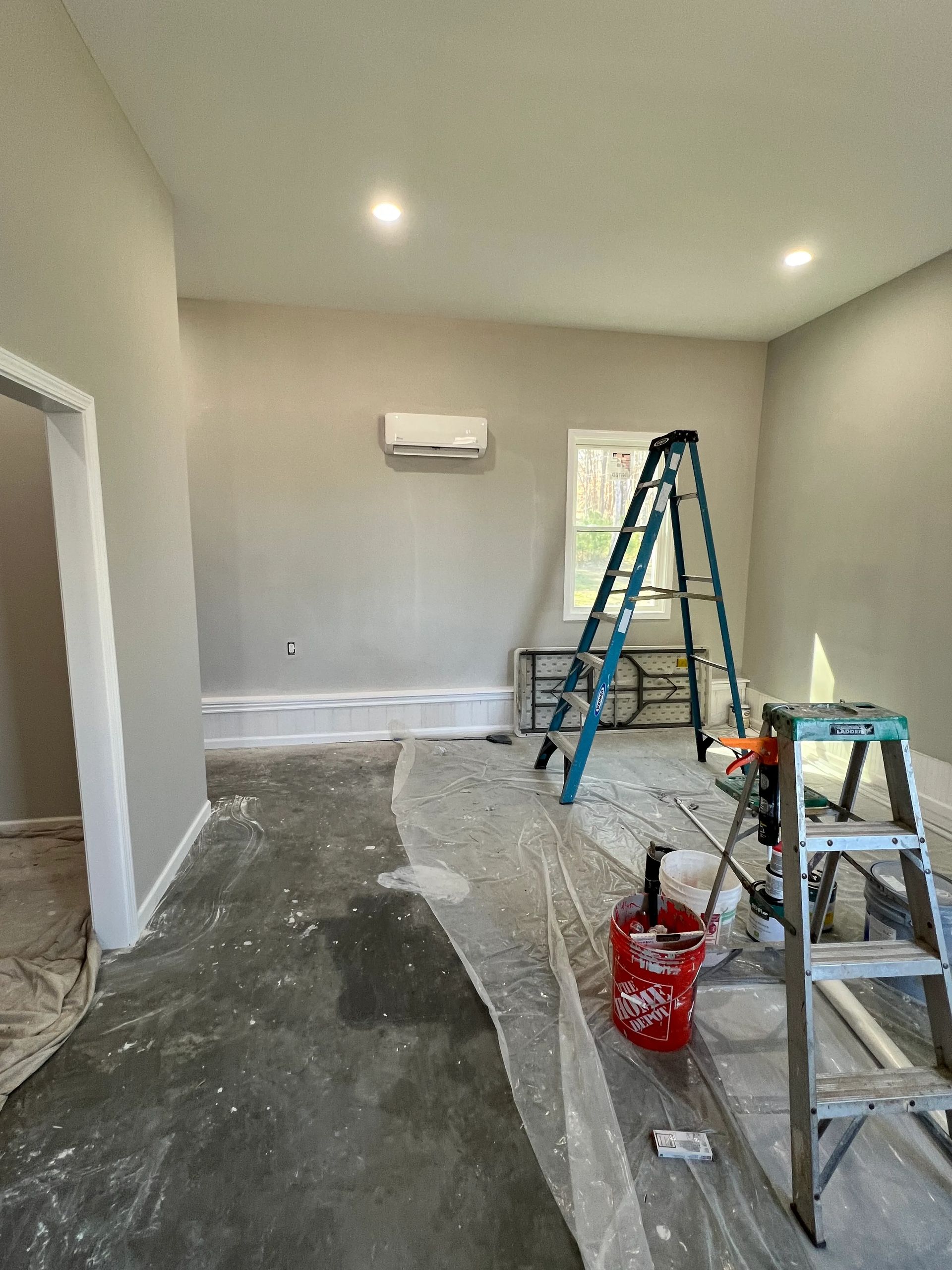 A room is being painted with a ladder and buckets of paint.