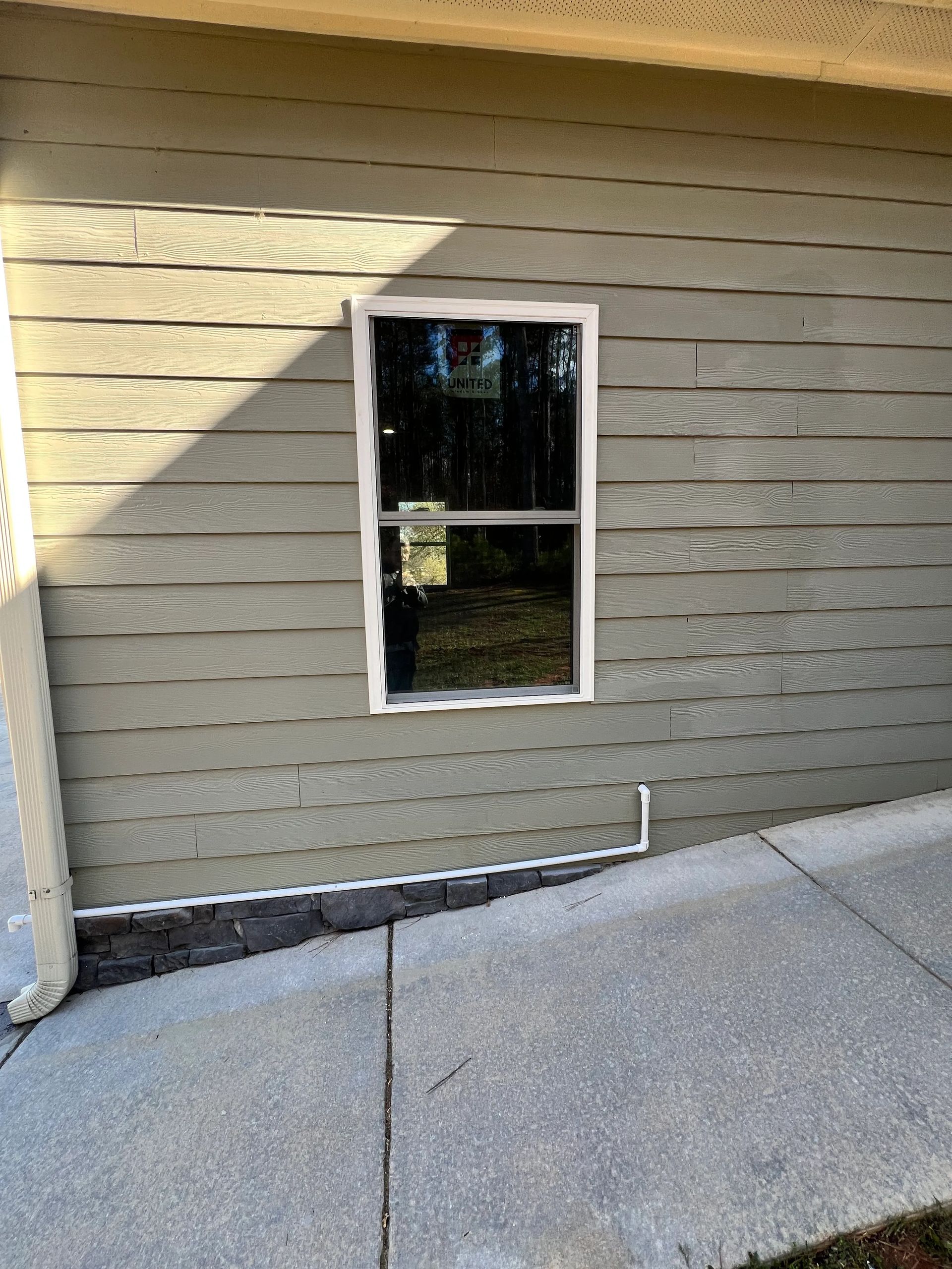A window on the side of a house next to a ramp.