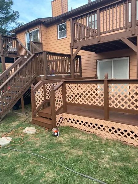 A wooden deck with stairs leading up to it is in front of a house.