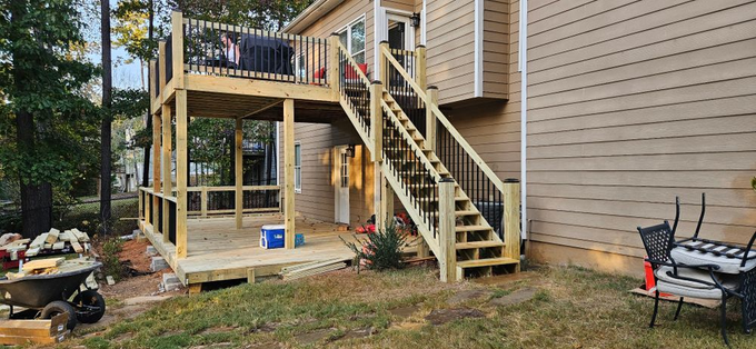 A wooden deck with stairs leading up to it is being built in the backyard of a house.