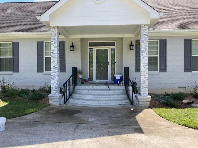 A white house with black shutters and a blue cooler in front of it