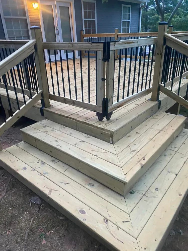 A wooden deck with stairs and a gate in front of a house.
