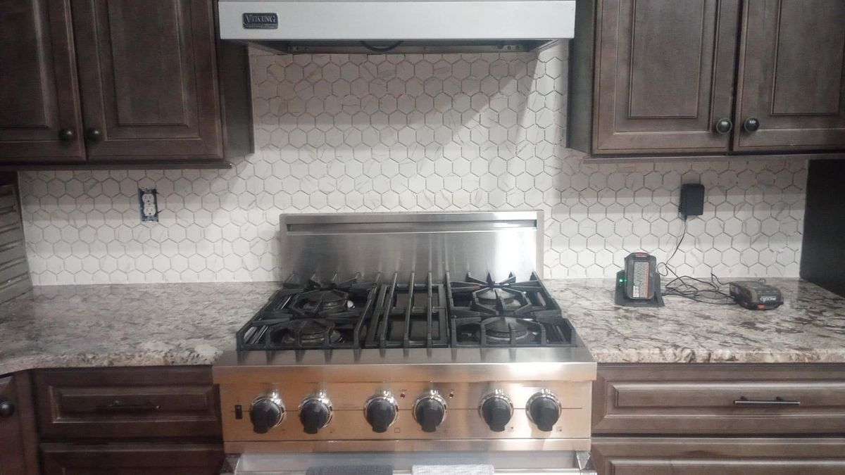 A stove top oven is sitting on top of a granite counter in a kitchen.