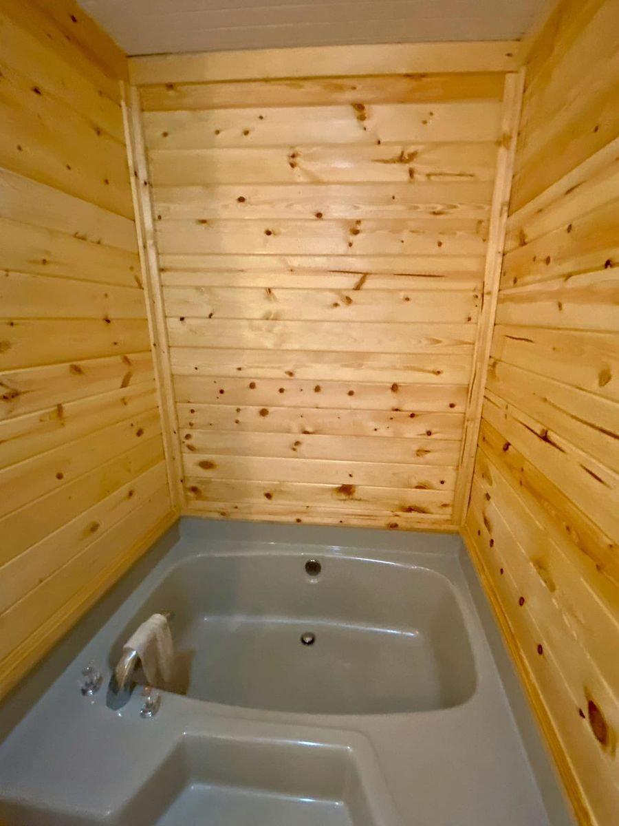 A bathtub in a bathroom with wood paneling on the walls