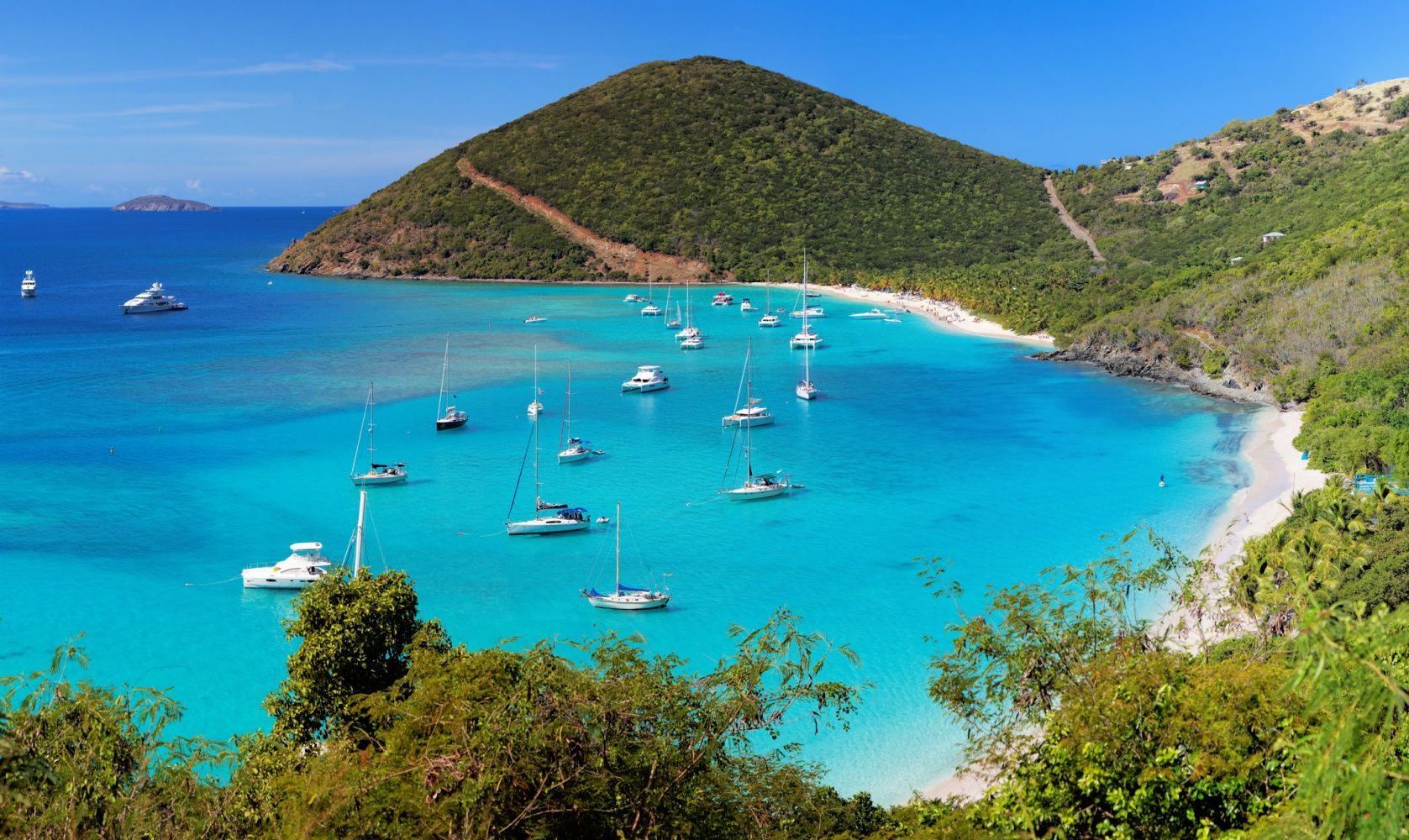 A couple standing on a beach at sunset with umbrellas and chairs.