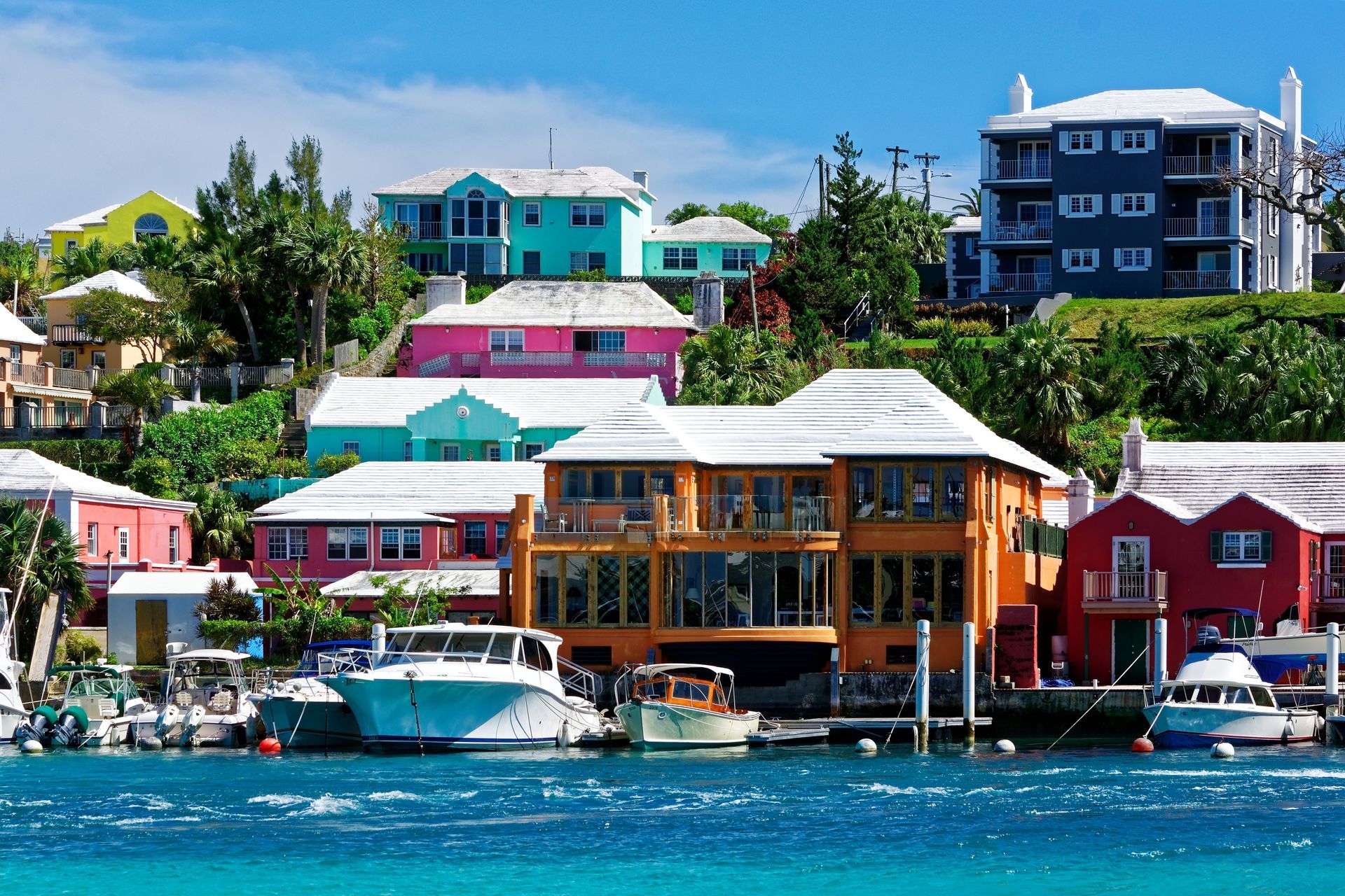 Colorful houses and docked boats on a waterfront in Bermuda. Houses are painted in bright colors like pink, blue, and orange.