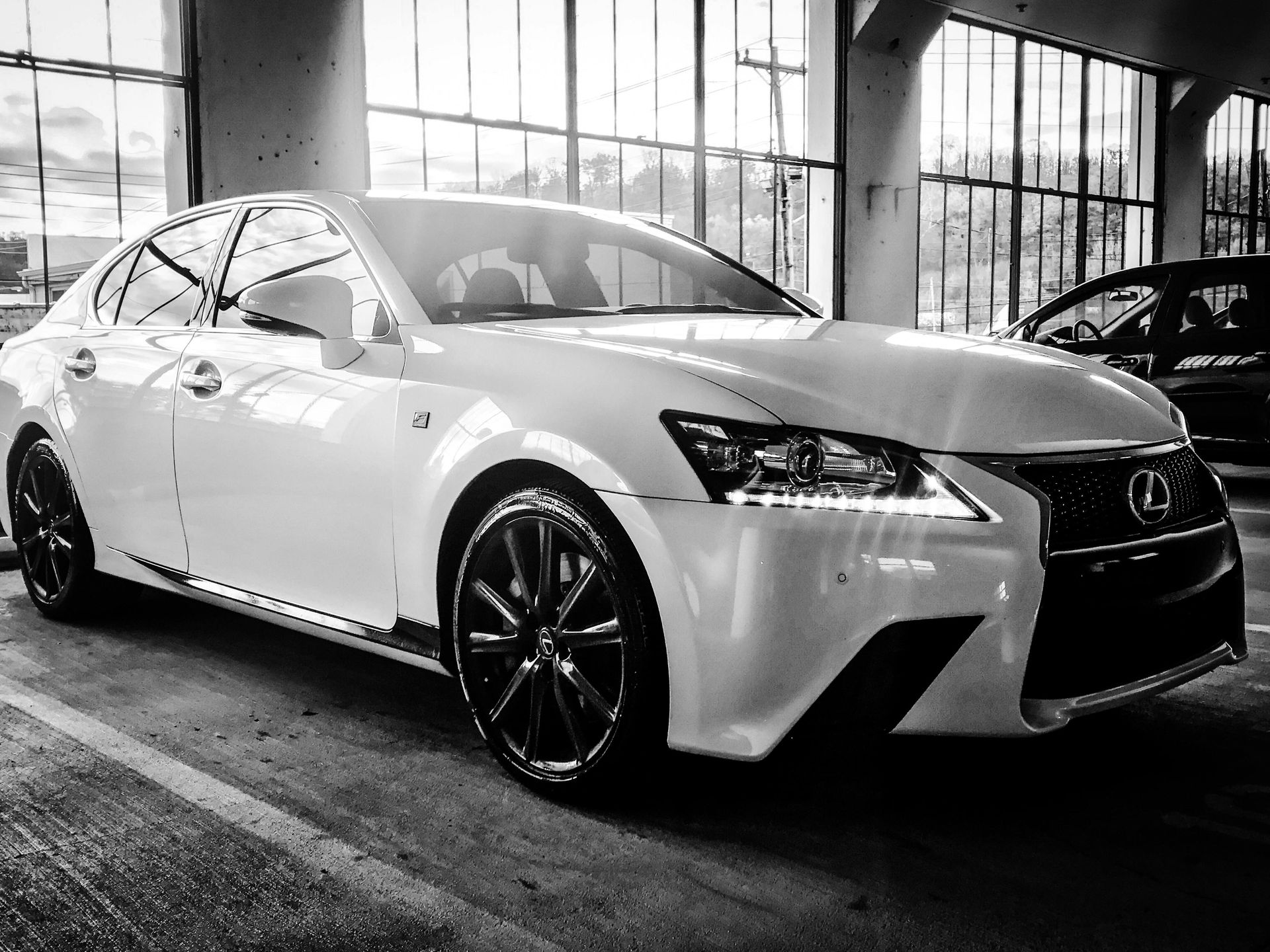 White Lexus sedan parked in a garage, black wheels, daytime.