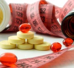 A stack of pills and a measuring tape on a table.