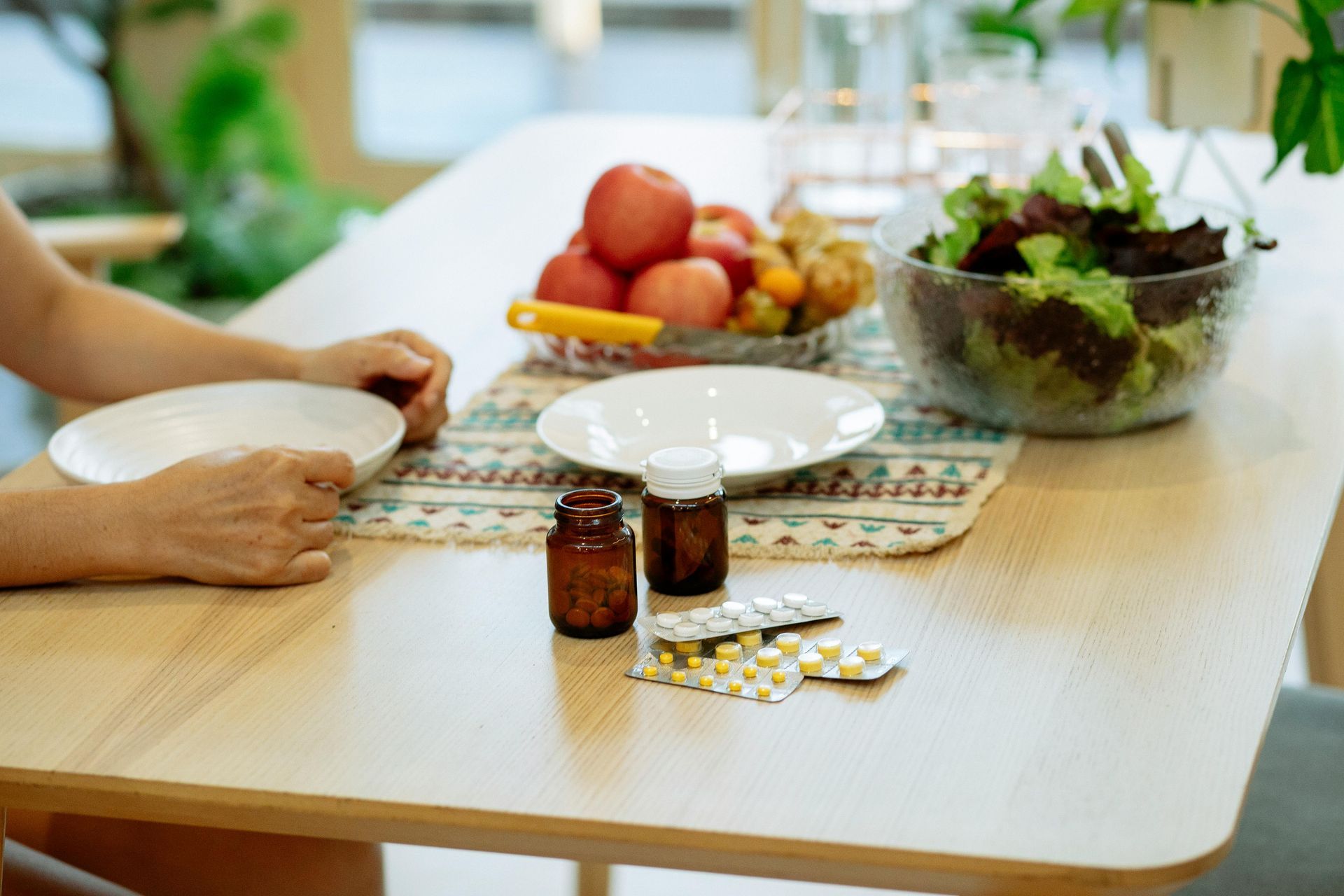 A woman is sitting at a table with a bowl of food and a bowl of fruit.