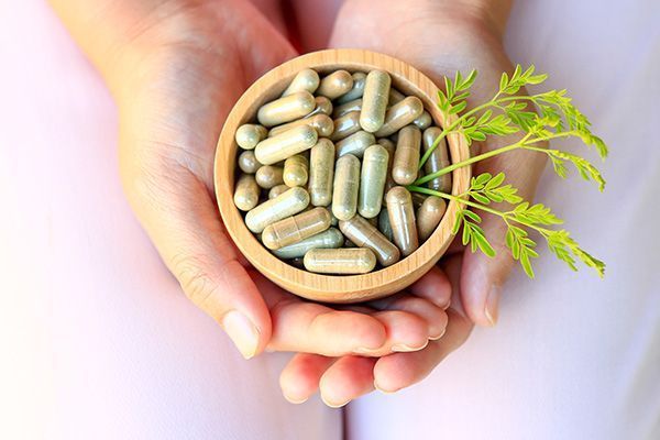 A person is holding a bowl of pills in their hands.