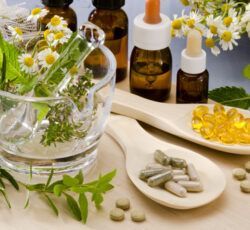 A mortar and pestle filled with herbs and pills on a table.