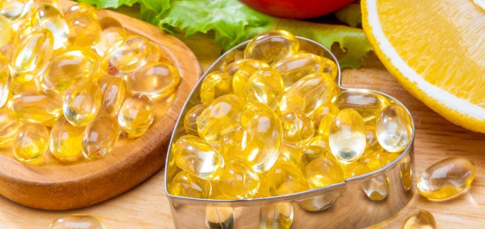 A heart shaped cookie cutter filled with fish oil capsules on a wooden table.