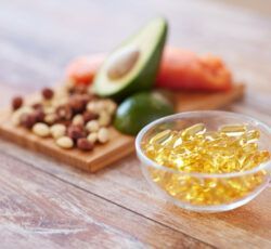 There is a bowl of fish oil next to a bowl of nuts and fruit.