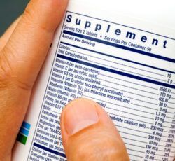 A person is holding a bottle of supplements and reading the label.