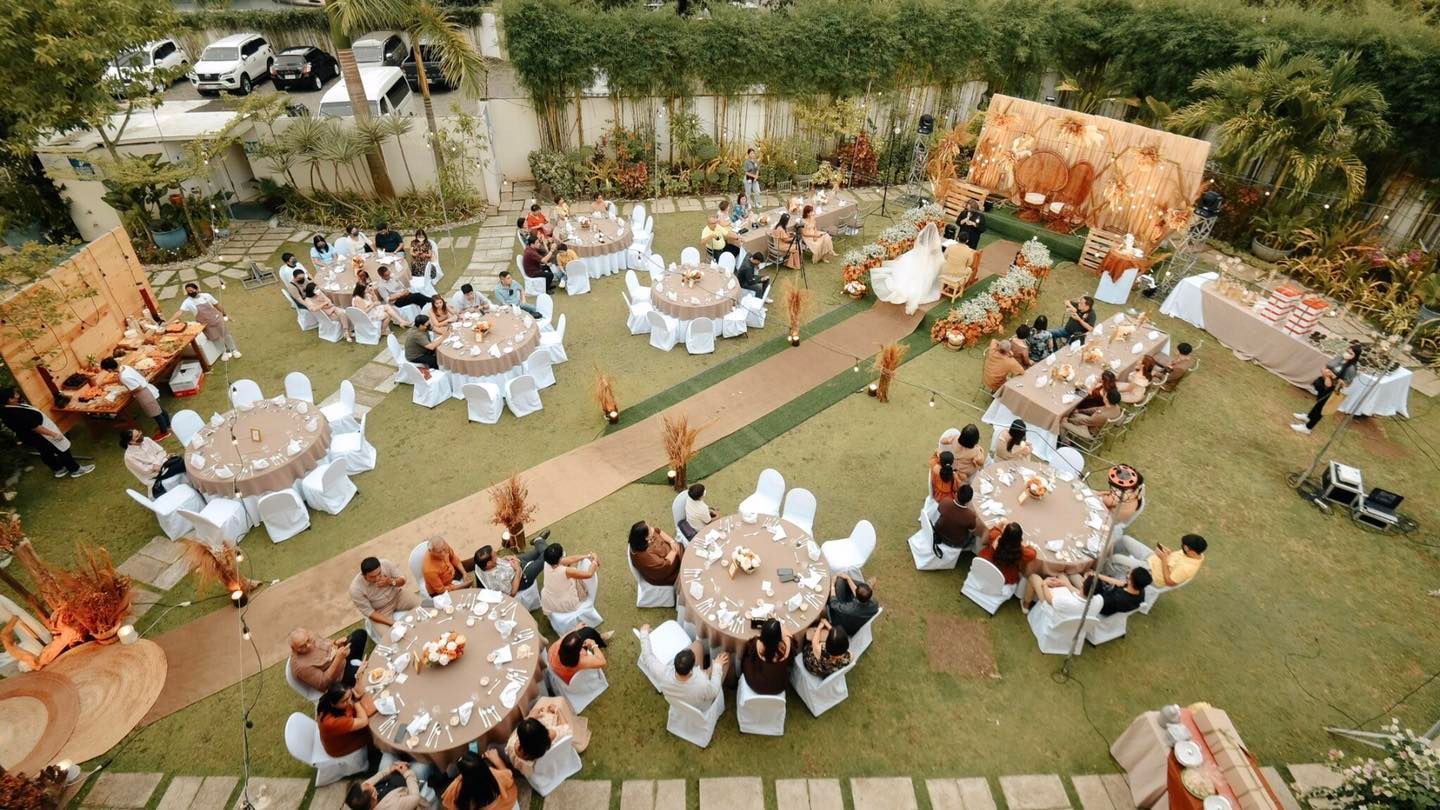 Outdoor wedding reception with round tables, a bride, and guests on a lawn.